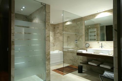 y baño con ducha acristalada y lavamanos. en Finca Prats Hotel Golf & Spa en Lleida