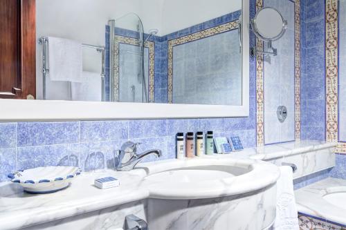 a bathroom with a white sink and a mirror at Grand Hotel de la Ville in Sorrento