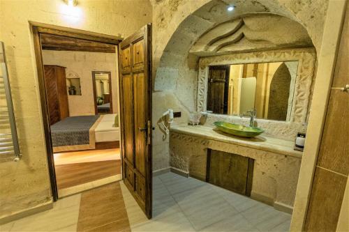 a bathroom with a sink and a mirror and a bed at Mimi Cappadocia Luxury Cave Hotel in Uchisar