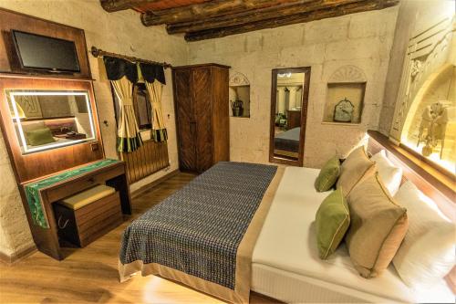 a bedroom with a bed and a television in it at Mimi Cappadocia Luxury Cave Hotel in Uchisar