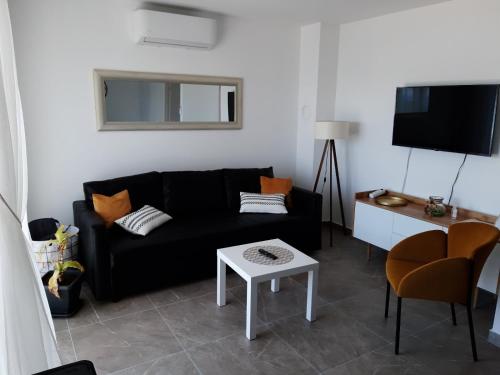 Gita Apartmani في سيزيتشي: غرفة معيشة مع أريكة سوداء وطاولة