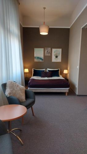 a bedroom with a bed and a chair and a table at Hotel Piano in Szeged