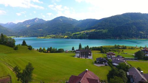 a house on a green hill next to a lake at Haus Schmied in Weissensee