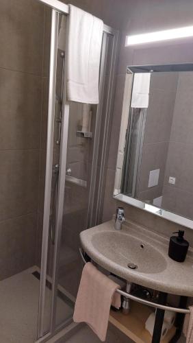 a bathroom with a sink and a shower with a mirror at Hotel Piano in Szeged