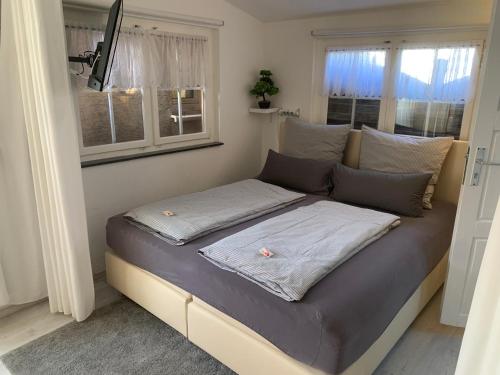 łóżko w pokoju z 2 oknami w obiekcie Holzhaus Leverkusen w mieście Leverkusen