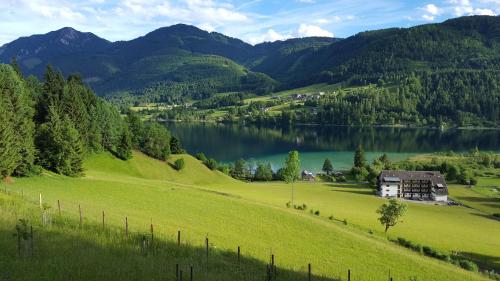 a house on a hill next to a lake at Haus Schmied in Weissensee