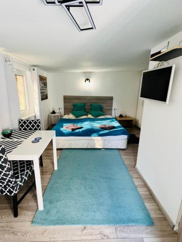 a bedroom with a bed and a table and a tv at Balcsitthon Apartmanok in Siófok