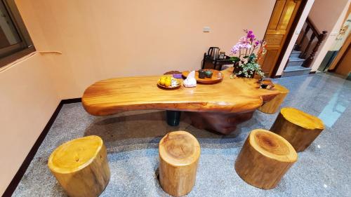 drewniany stół z kilkoma kłodami wokół niego w obiekcie Roam Sanyi Hostel w mieście Sanyi