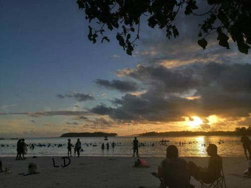 a group of people on the beach at sunset at Vacances Le Nereide Blue Bay in Blue Bay