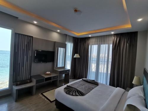 a hotel room with a bed and a tv and windows at Jewel Beach Matrouh Hotel in Marsa Matruh