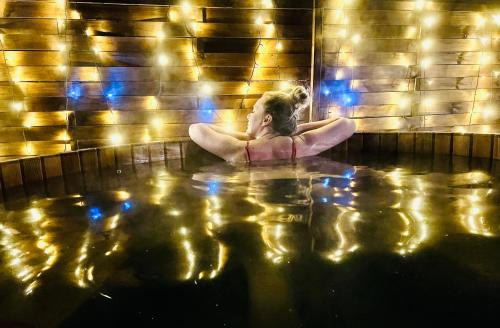 a woman sitting in a bath tub with lights at Balcsitthon Apartmanok in Siófok