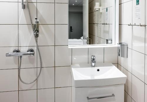 a white bathroom with a sink and a shower at Go Hotel Saga in Copenhagen