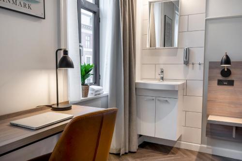 a bathroom with a desk with a sink and a mirror at Go Hotel Saga in Copenhagen