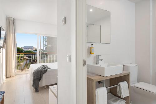 Baño blanco con lavabo y espejo en Hotel Atolon, en Cala Bona