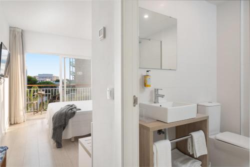 a white bathroom with a sink and a mirror at Hotel Atolon in Cala Bona