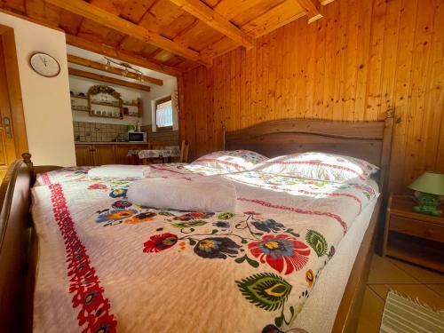 1 dormitorio con 1 cama con manta de flores en Chata Patrícia, en Liptovský Michal