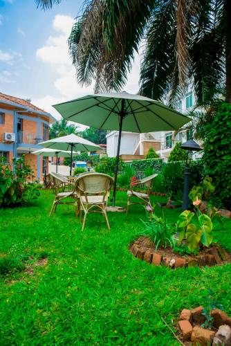 a table and chairs with an umbrella in the grass at One Click Hotel in Kigali