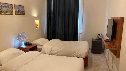 a hotel room with two beds and a flat screen tv at New Park Hotel in Amman