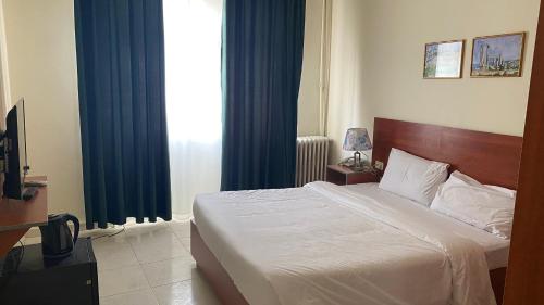 a bedroom with a bed and a window with blue curtains at New Park Hotel in Amman