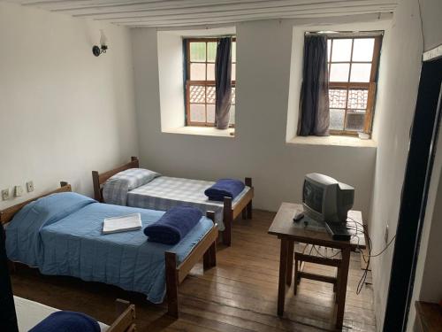 um quarto com três camas e uma tv nele em Pousada Vila Rica em Ouro Preto