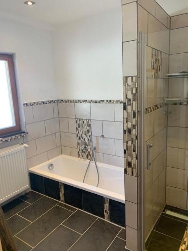 y baño con bañera y ducha. en Ferienwohnung Maier Schliersee Neuhaus, en Schliersee