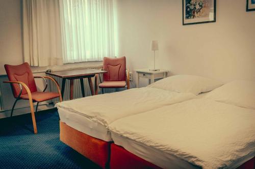 a hotel room with a bed and two chairs and a table at Inselgaestehaus-Erna in Putbus