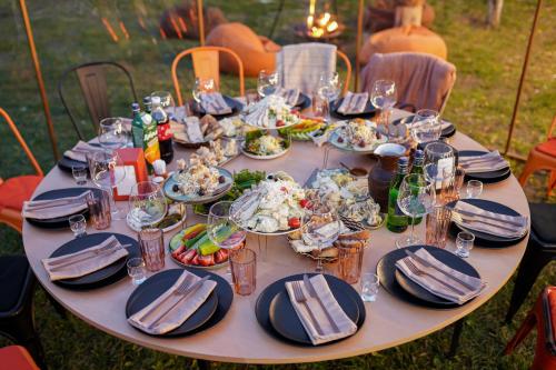 a table with plates of food and wine glasses at Domes Town by ANGAR in Vahagnadzor