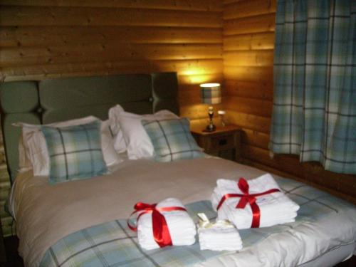 a bed with two towels and bows on it at Pheasant Lodge Scottish Borders in Carlisle