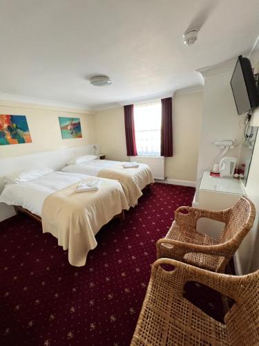 a hotel room with two beds and a television at Melbourne House Hotel in London