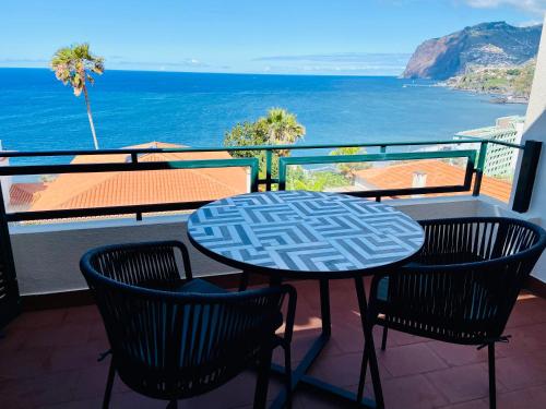 una mesa y sillas en un balcón con vistas al océano en Ocean Cliffs Apartments, en Funchal