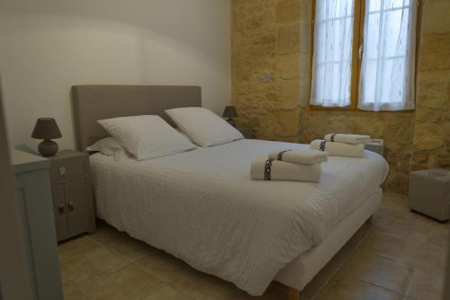 une chambre avec un lit blanc avec des serviettes dessus dans l'établissement Gloria Location, à Sarlat-la-Canéda