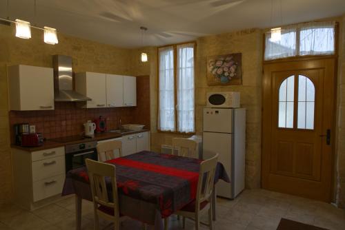 une cuisine avec une table et un réfrigérateur blanc dans l'établissement Gloria Location, à Sarlat-la-Canéda