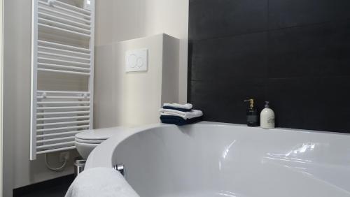 een badkamer met een wit bad en een toilet bij Côté Grange in Tournai