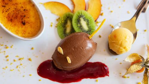 a white plate with a dessert with fruit and sauce at Schwarzwaldhotel Oberwiesenhof in Seewald
