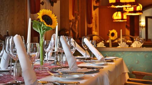 a table with plates and glasses and a sunflower on it at Schwarzwaldhotel Oberwiesenhof in Seewald