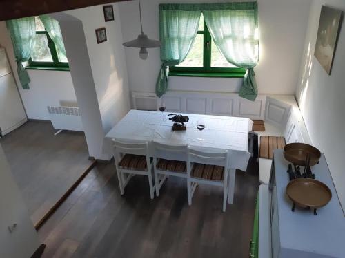 una mesa blanca y sillas en una habitación con 2 ventanas en Bakina iža, en Duga Resa