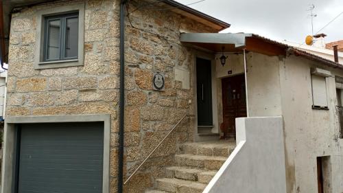 a brick house with a garage door and stairs at Casa do Pelourinho - T1 in Loriga