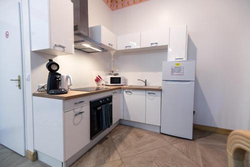 a small kitchen with white cabinets and a refrigerator at Studio Romantique Maison de L'église du Couvent in Narbonne