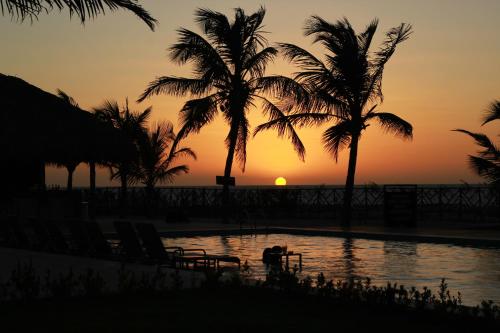 a sunset at the beach with palm trees and a pool at Manati in Barra Grande