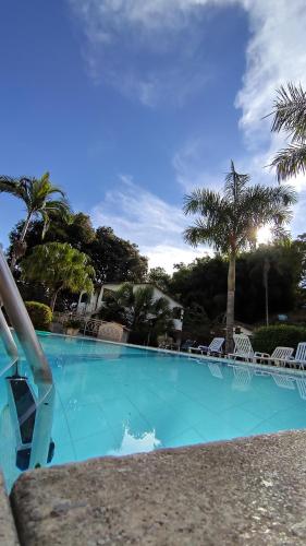 een groot blauw zwembad met stoelen en palmbomen bij Pousada Chez Nous in Penedo