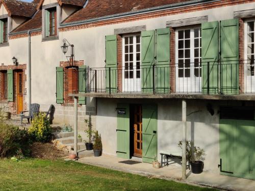 a building with green doors and a balcony at Chambres d'hôtes / B&B Chez Mon Rêve in Éguzon-Chantôme