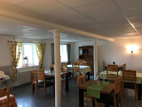 una sala da pranzo con tavoli e sedie e una sala con tavoli e sedie. di Hunnebergs Gård Hostel & Camping a Vargön