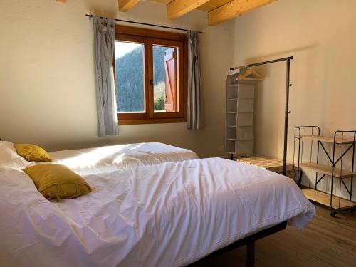 a bedroom with two white beds and a window at Balcón de Pineta in Bielsa