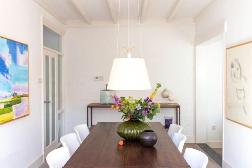 a dining room with a table with a vase of flowers at Karakteristieke visserswoning dichtbij het centrum in Joure