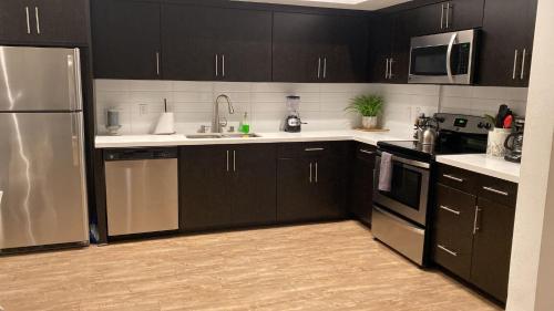 una cocina con armarios negros y electrodomésticos de acero inoxidable en Exceptional Loft FREE Parking and WIFI, en Los Ángeles