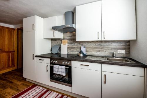 eine Küche mit weißen Schränken und einem Waschbecken in der Unterkunft Rainerhof in Murau