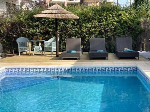 a swimming pool with two chairs and an umbrella at Casa Flora - Mijas Costa - Andalusië in Mijas