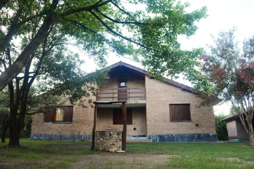 ein großes Backsteinhaus mit Bäumen davor in der Unterkunft El jagüel in Villa General Belgrano