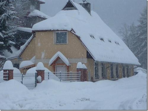 a house covered in snow with a pile of snow at Penzion U Štoly Jáchymov in Jáchymov