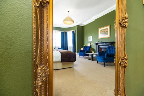 a mirror in a bedroom with a bed and blue chairs at Butler House in Kilkenny